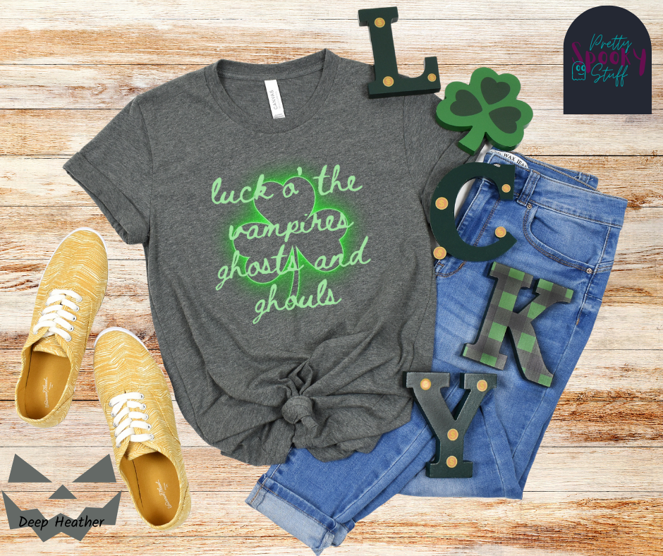 St. Patrick's Day shirt with transparent shamrock that glows green around the edges and the words "luck o' the vampires ghost and ghouls" in cursive light green font over top, in deep heather.