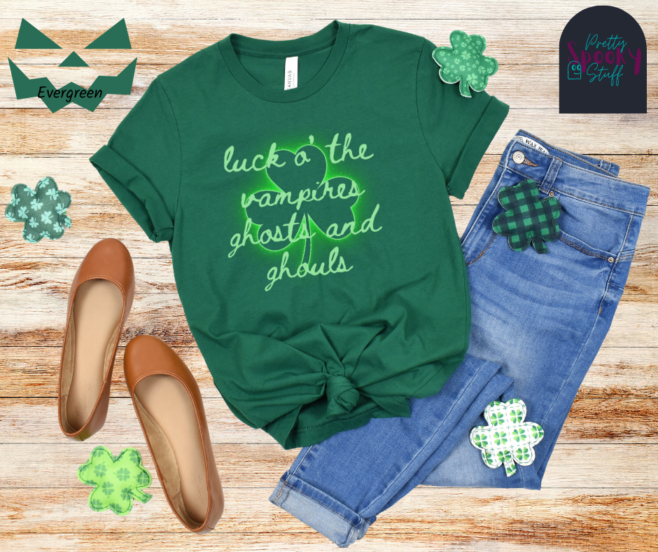 St. Patrick's Day shirt with transparent shamrock that glows green around the edges and the words "luck o' the vampires ghost and ghouls" in cursive light green font over top, in evergreen.