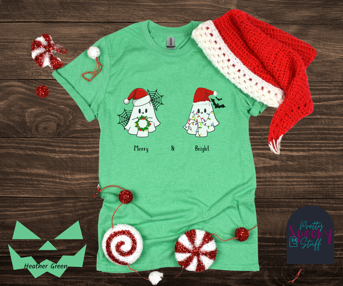Christmas shirt with two ghosts wearing santa hats, one holding a wreath with spiderwebs behind them, and one tangled in lights with bats behind them, named Merry and Bright, in heather green.