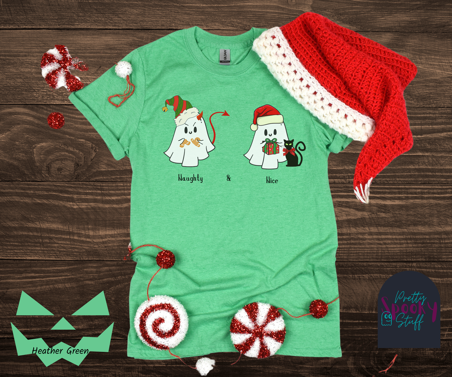 Christmas shirt with two ghosts wearing Santa hats, one named Naughty with a devil's tail and horn breaking a gingerbread man, and one named Nice holding a wrapped gift with a bow-wearing black cat next to them, in heather green.