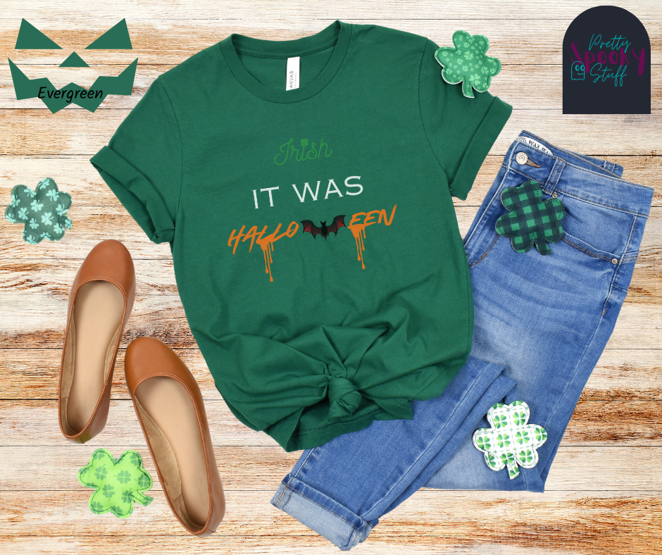St. Patrick's Day shirt with the word "Irish" in green and a clover for the "I" dot, the words "it was" in white all uppercase, and "Halloween" in orange with a bat in place of the "w" and orange blood drips off two letters, in evergreen.