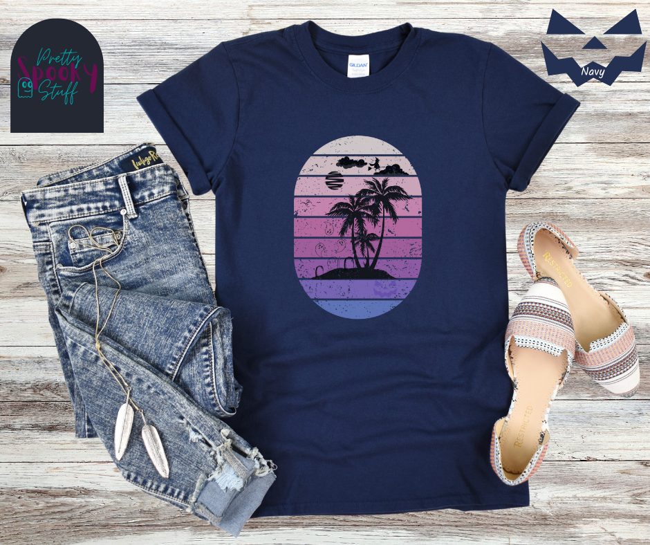 Summerween shirt with oval purple gradient lines, behind small beach and palm trees silhouette, that also has three gravestones on the beach with several ghosts flying above, as well as a witch flying on her broom in the clouds, in navy.