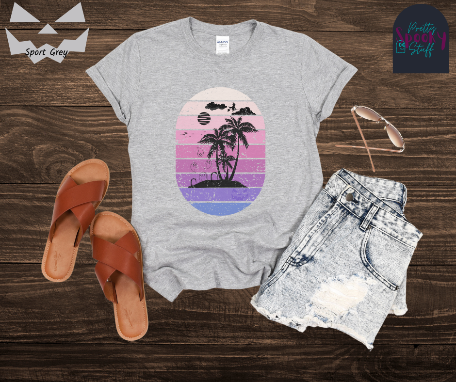 Summerween shirt with oval purple gradient lines, behind small beach and palm trees silhouette, that also has three gravestones on the beach with several ghosts flying above, as well as a witch flying on her broom in the clouds, in sport grey.