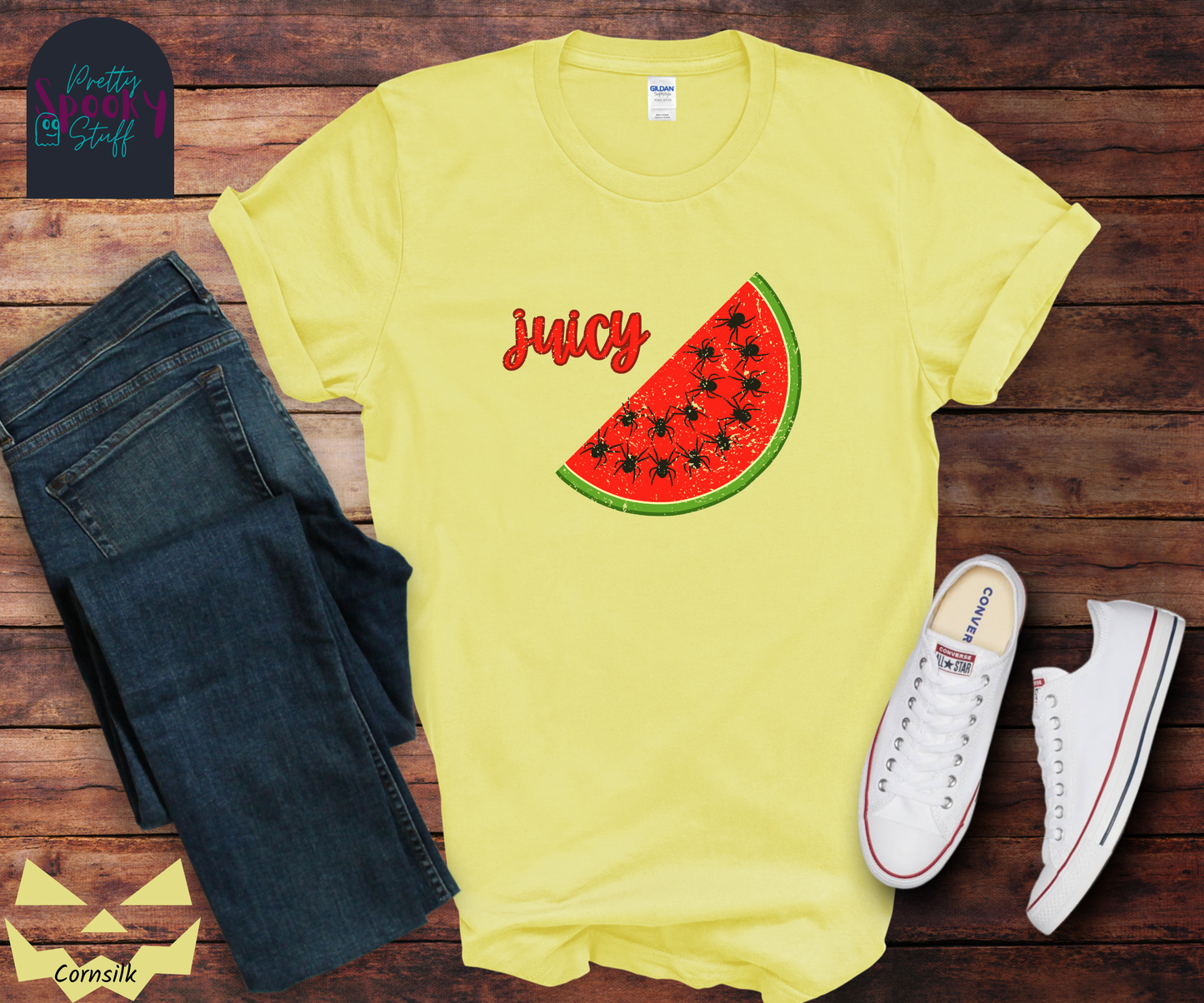 Summer watermelon shirt with a slice of watermelon where black spiders replace seeds, and the word "juicy" in red cursive font, vintage look, in cornsilk.