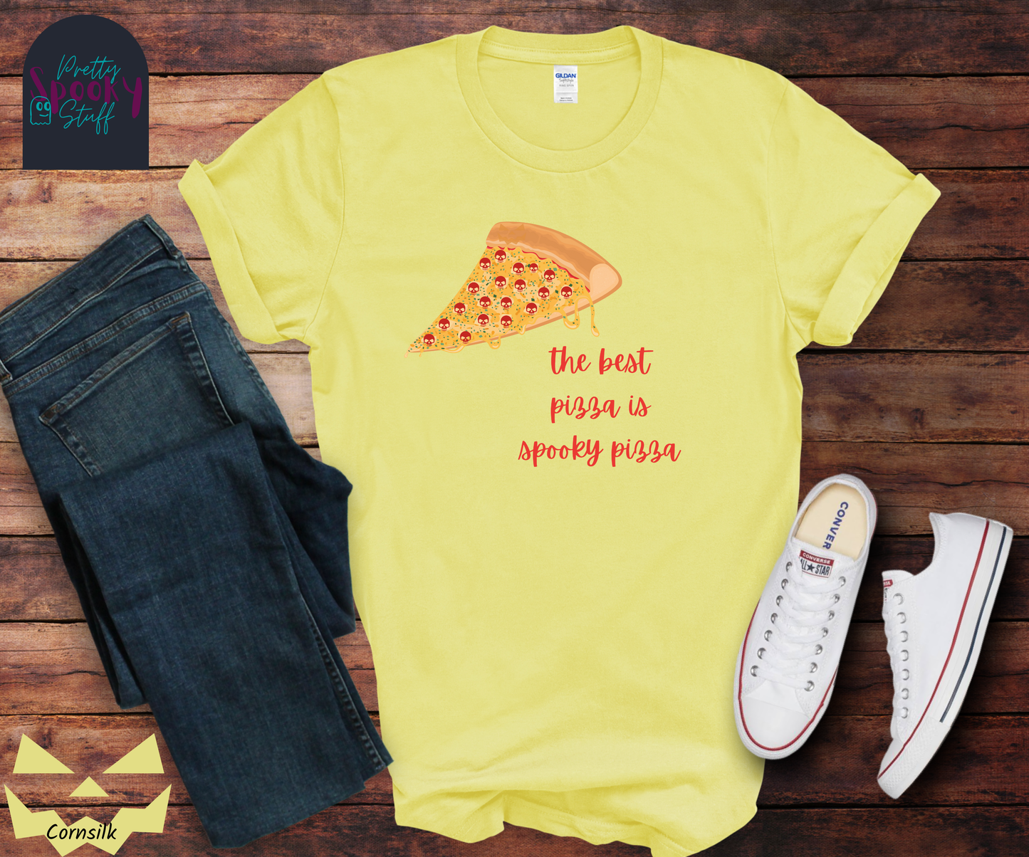 Pizza shirt with a slice of pepperoni pizza with skull shaped pepperonis and the words "the best pizza is spooky pizza" in red cursive font, in cornsilk.