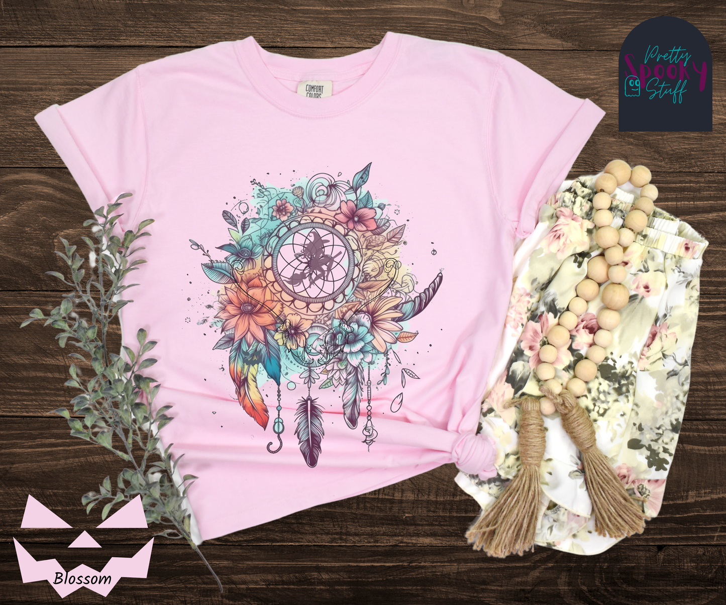 Halloween floral witch dreamcatcher shirt, watercolor aesthetic in blues and pinks, with purple silhouette of witch flying on her broom in the main circle, with witch broom line drawings hidden amongst the flowers, in blossom.