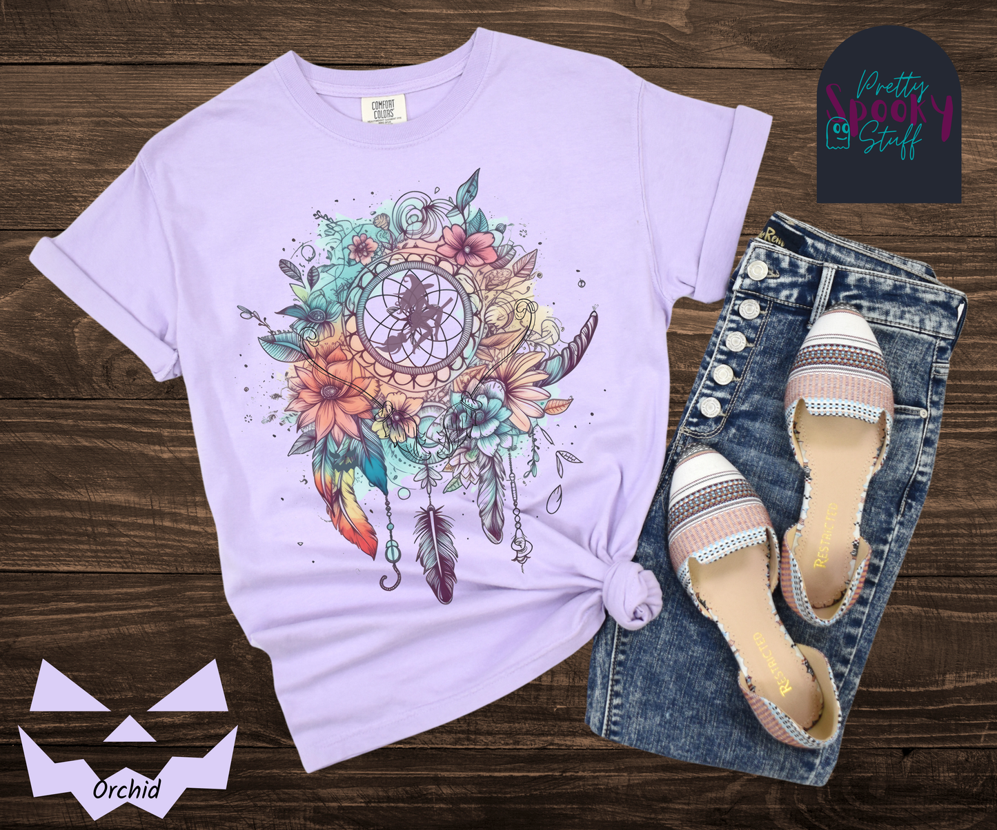 Halloween floral witch dreamcatcher shirt, watercolor aesthetic in blues and pinks, with purple silhouette of witch flying on her broom in the main circle, with witch broom line drawings hidden amongst the flowers, in orchid.