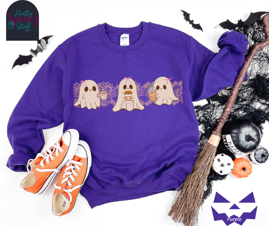 Coquette Halloween sweatshirt with three adorable ghosts, each enjoying their own coffee beverage, adorned with a pink bow, with light pink intricate lace design behind them, in purple.