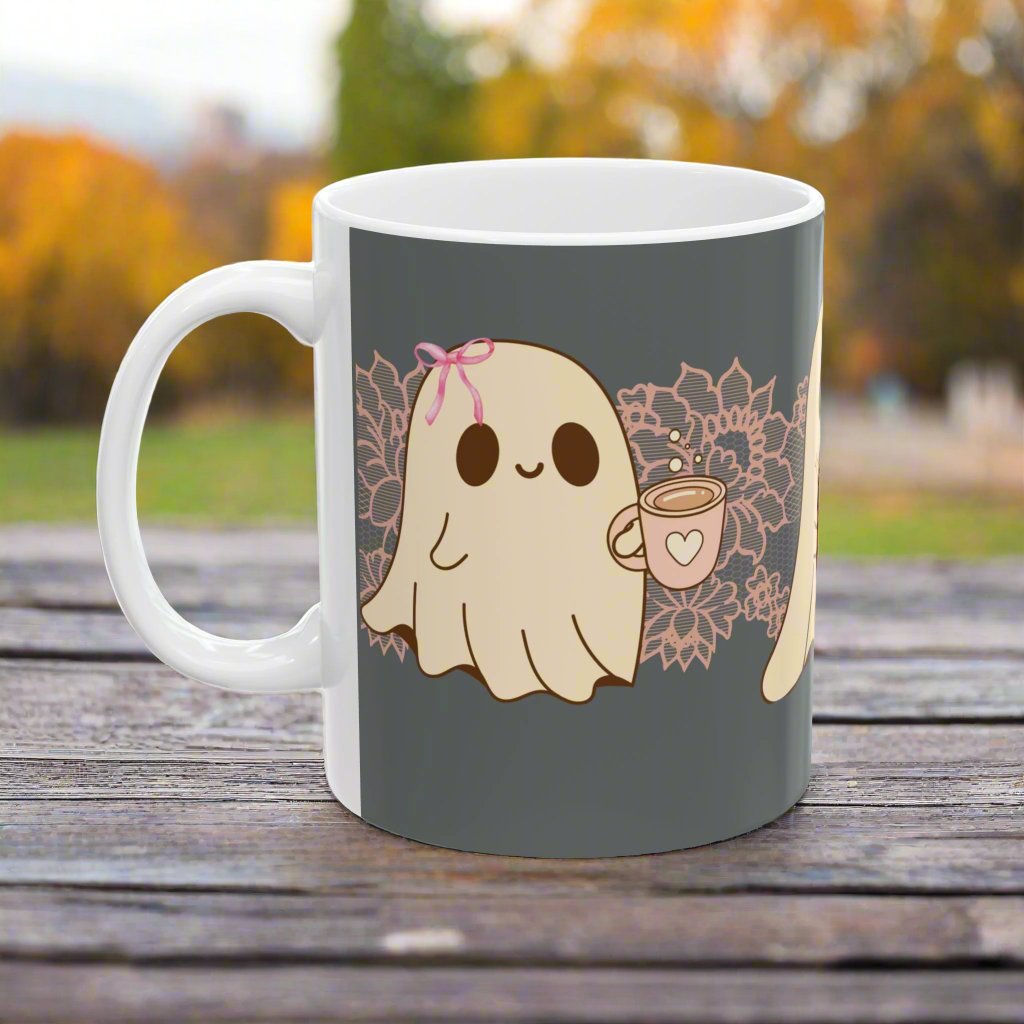 Ceramic Halloween coffee mug with three adorable ghosts, each enjoying their own coffee beverage, adorned with a pink bow, with light pink intricate lace design behind them, gray background, side view.