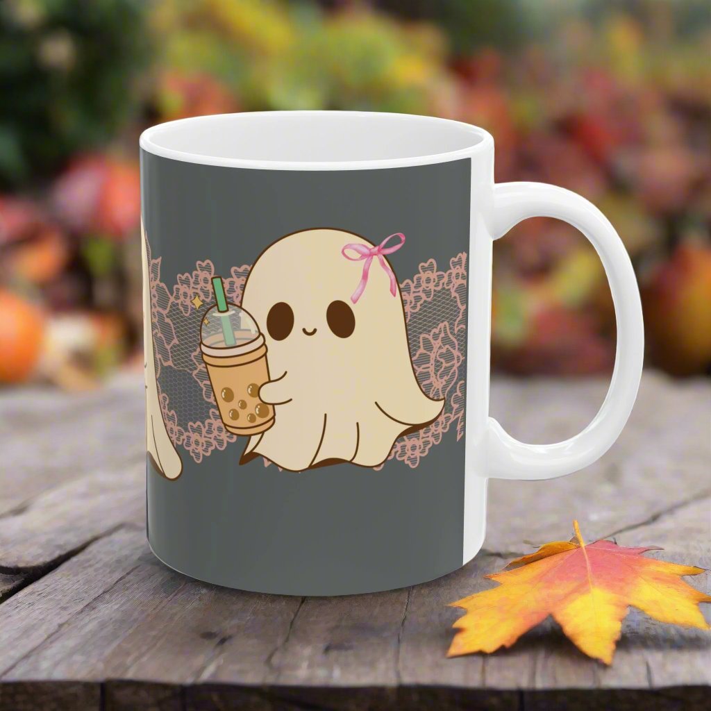 Ceramic Halloween coffee mug with three adorable ghosts, each enjoying their own coffee beverage, adorned with a pink bow, with light pink intricate lace design behind them, gray background, other side view.