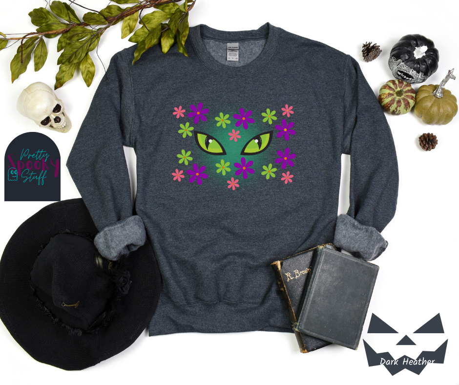 Cat Halloween sweatshirt with spooky green cat eyes in the middle of purple, pink and green flowers, with a blue glow behind them, in dark heather.