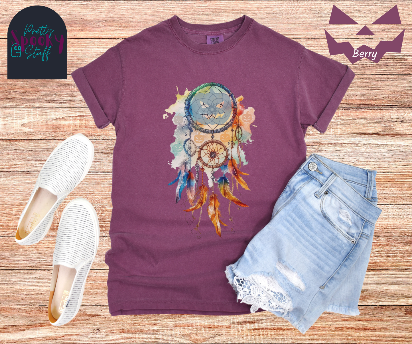 Halloween pumpkin dream catcher shirt, watercolor aesthetic in rusts, peaches, and light blues, with three small circles and 6 feathers hanging from the main circle that features a light blue jack o' lantern silhouette, several more jack o' lanterns hide amongst the colors, in berry.