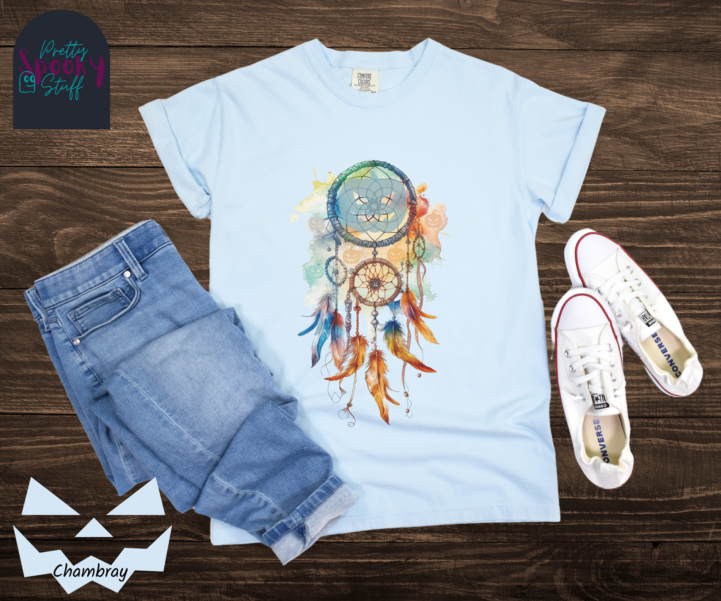 Halloween pumpkin dream catcher shirt, watercolor aesthetic in rusts, peaches, and light blues, with three small circles and 6 feathers hanging from the main circle that features a light blue jack o' lantern silhouette, several more jack o' lanterns hide amongst the colors, in chambray.