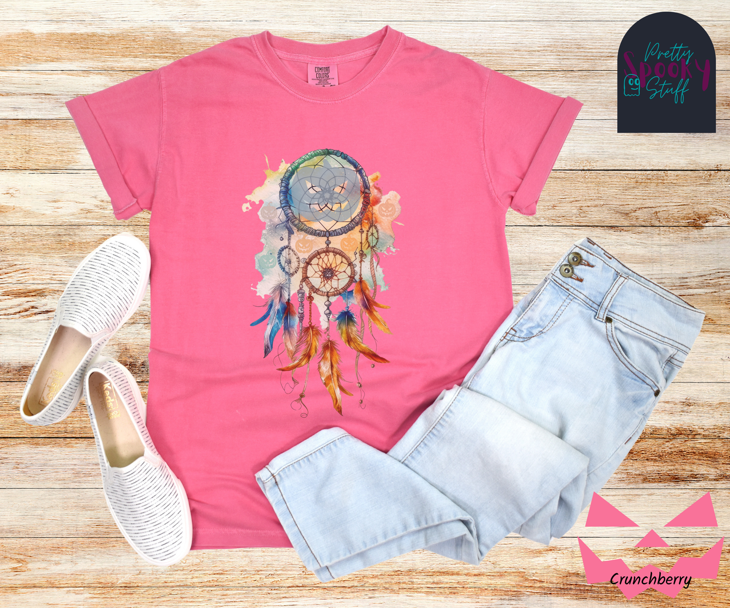 Halloween pumpkin dream catcher shirt, watercolor aesthetic in rusts, peaches, and light blues, with three small circles and 6 feathers hanging from the main circle that features a light blue jack o' lantern silhouette, several more jack o' lanterns hide amongst the colors, in crunchberry.