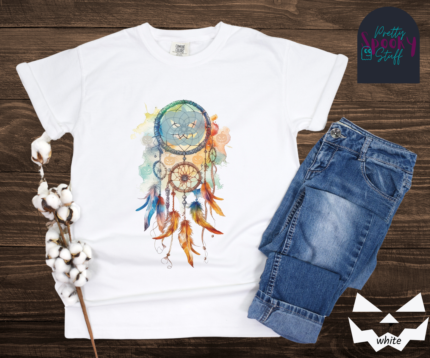 Halloween pumpkin dream catcher shirt, watercolor aesthetic in rusts, peaches, and light blues, with three small circles and 6 feathers hanging from the main circle that features a light blue jack o' lantern silhouette, several more jack o' lanterns hide amongst the colors, in white.