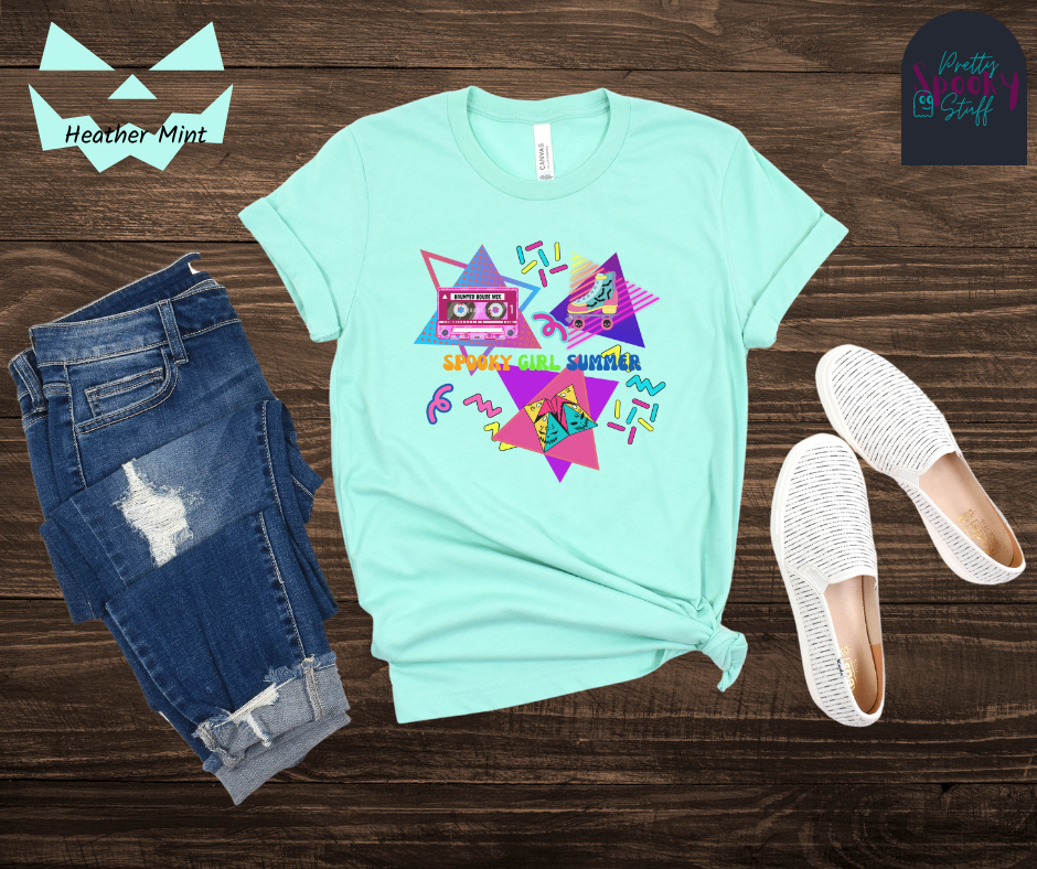 Summerween unisex tee featuring retro 90's design including cassette tape with "haunted house mix", bat covered roller skate, folded paper fortune teller, bright-colored squiggles, and words "spooky girl summer" across the middle in orange, green, and dark blue, in heather mint.