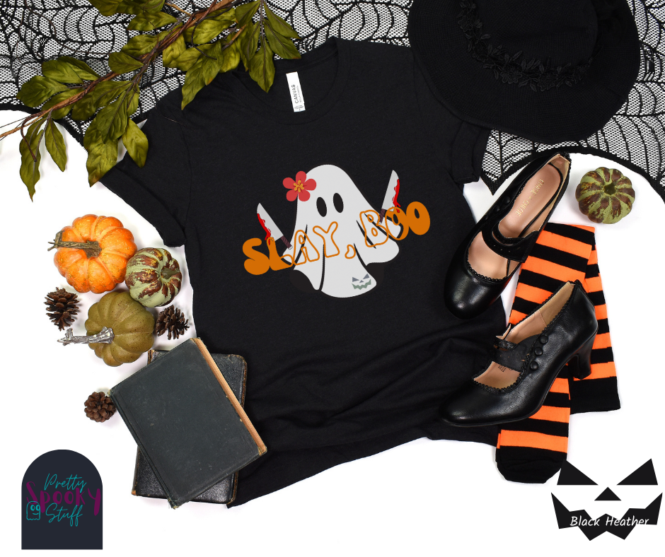 Ghost Halloween shirt with a ghost wearing pink flower, holding two bloody butcher knives and the words "slay boo" in orangle font in front of her, in black heather.