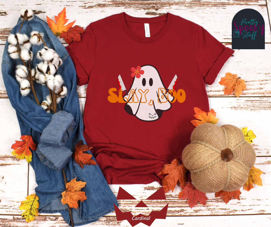 Ghost Halloween shirt with a ghost wearing pink flower, holding two bloody butcher knives and the words "slay boo" in orangle font in front of her, in cardinal.