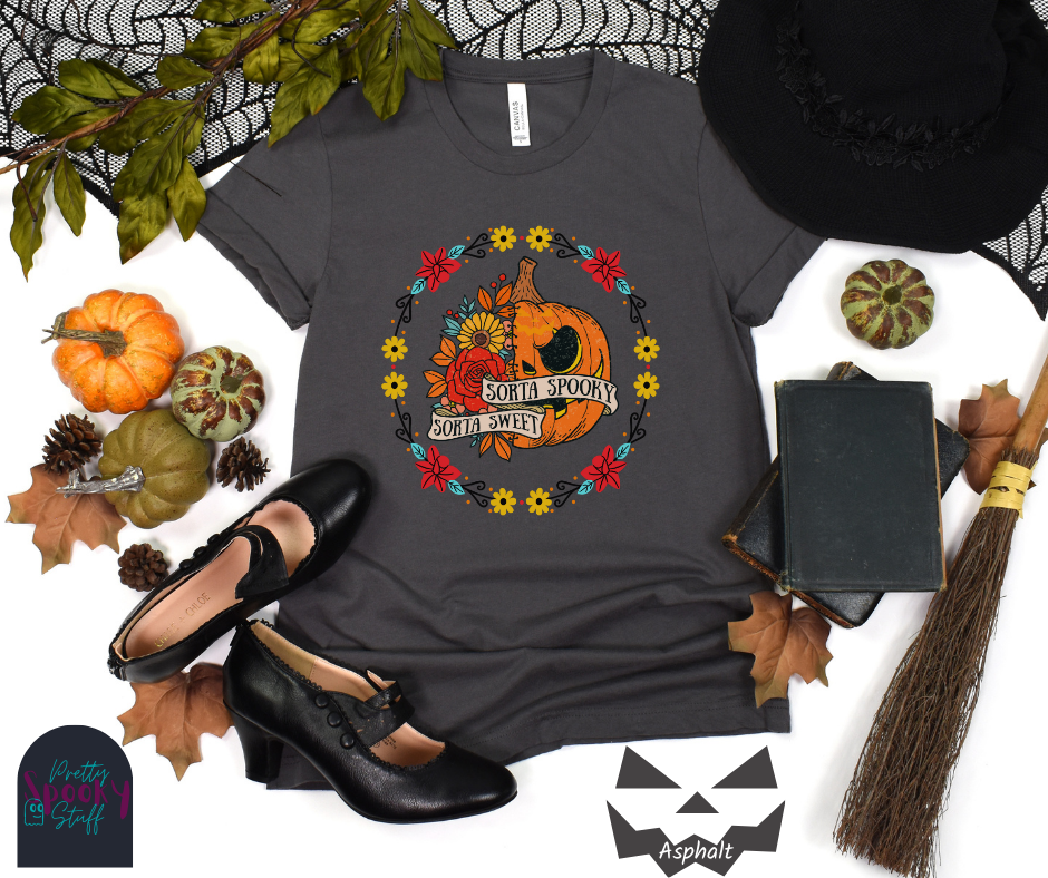 Pumpkin Halloween shirt with a circle of yellow, red, and blue flowers, surrounding a half jack o' lantern half floral design with the words "sorta sweet sorta spooky" on banners, in asphalt.