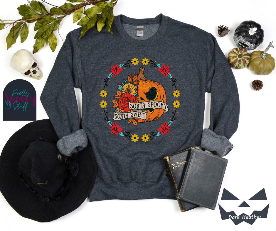 Halloween sweatshirt with a circle of yellow, red, and blue flowers, surrounding a half jack o'lantern half floral design with the words "sorta sweet sorta spooky" on banners, in dark heather.