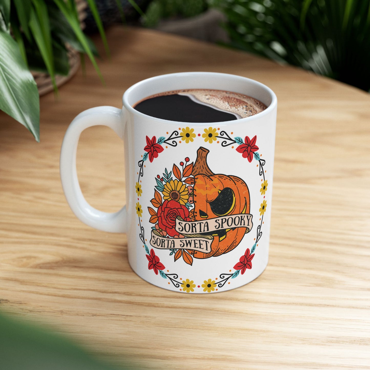Halloween mug with a circle of yellow, red, and blue flowers, surrounding a half jack o' lantern half floral design with the words "sorta sweet sorta spooky" on small banners across the front, side view.