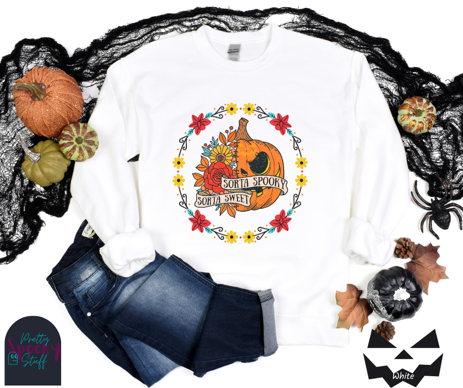 Halloween sweatshirt with a circle of yellow, red, and blue flowers, surrounding a half jack o'lantern half floral design with the words "sorta sweet sorta spooky" on banners, in white.