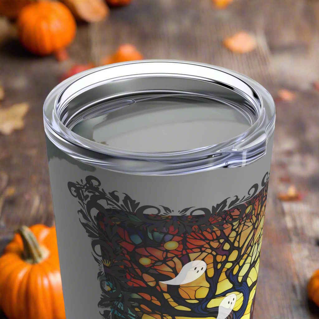 20 ounce insulated tumbler with stained glass design featuring a bare tree reaching upwards and ghosts flying all around, view of top and clear lid.