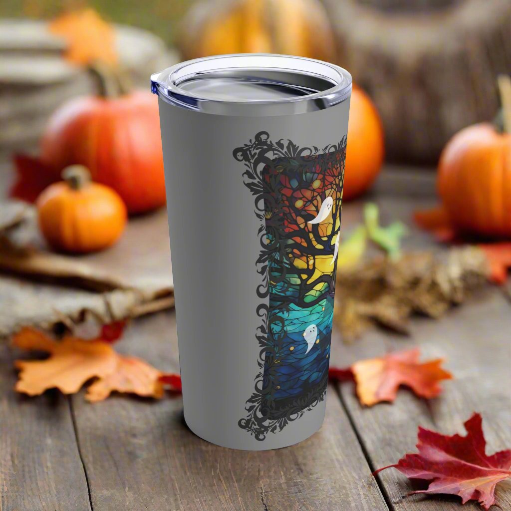 20 ounce insulated tumbler with stained glass design featuring a bare tree reaching upwards and ghosts flying all around., side view.