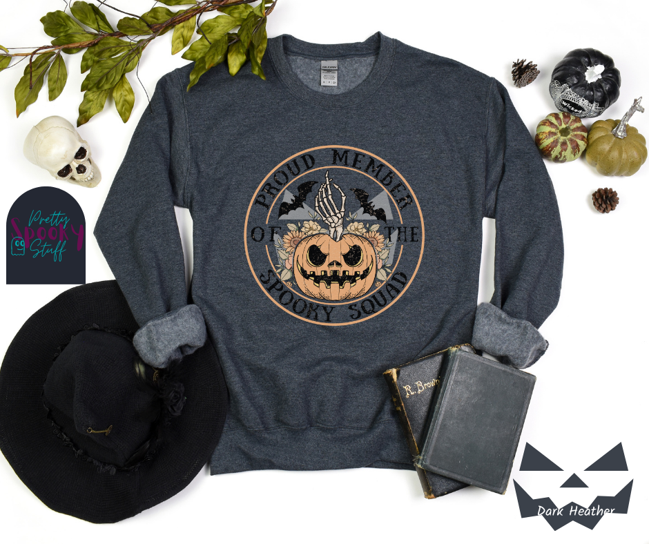 Halloween sweatshirt with a skeleton hand coming out of a jack o lantern with flowers behind it, two bats above it, surrounded by the words "proud member of the spooky squad" in a circle, in dark heather.
