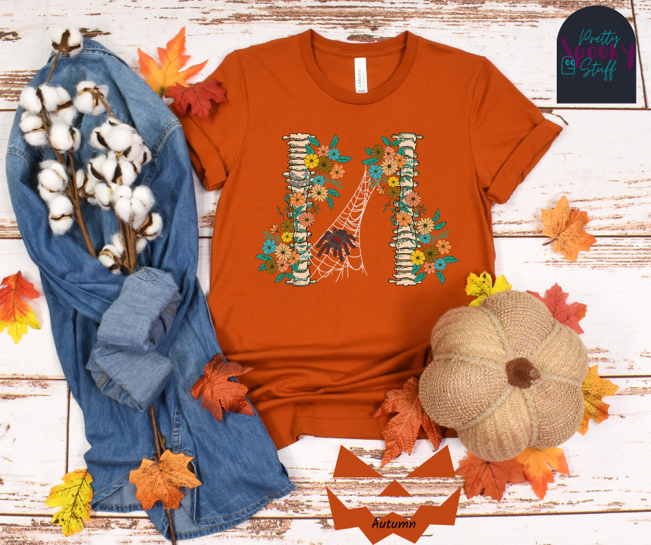 Spider Halloween shirt with two spine bones wrapped in vintage flowers, and a tarantula spider on a web between the two, in autumn.