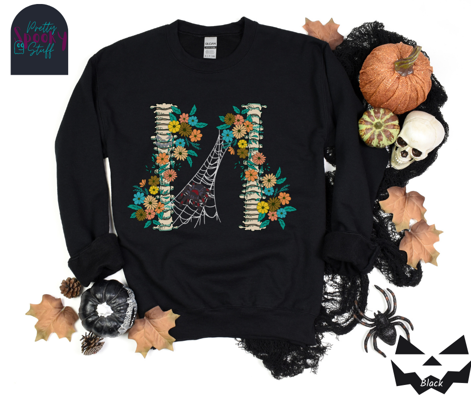 Spider Halloween sweatshirt with two spine bones wrapped in vintage flowers, and a tarantula spider on a web between the two, in black.