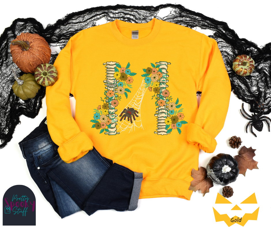 Spider Halloween sweatshirt with two spine bones wrapped in vintage flowers, and a tarantula spider on a web between the two, in gold.