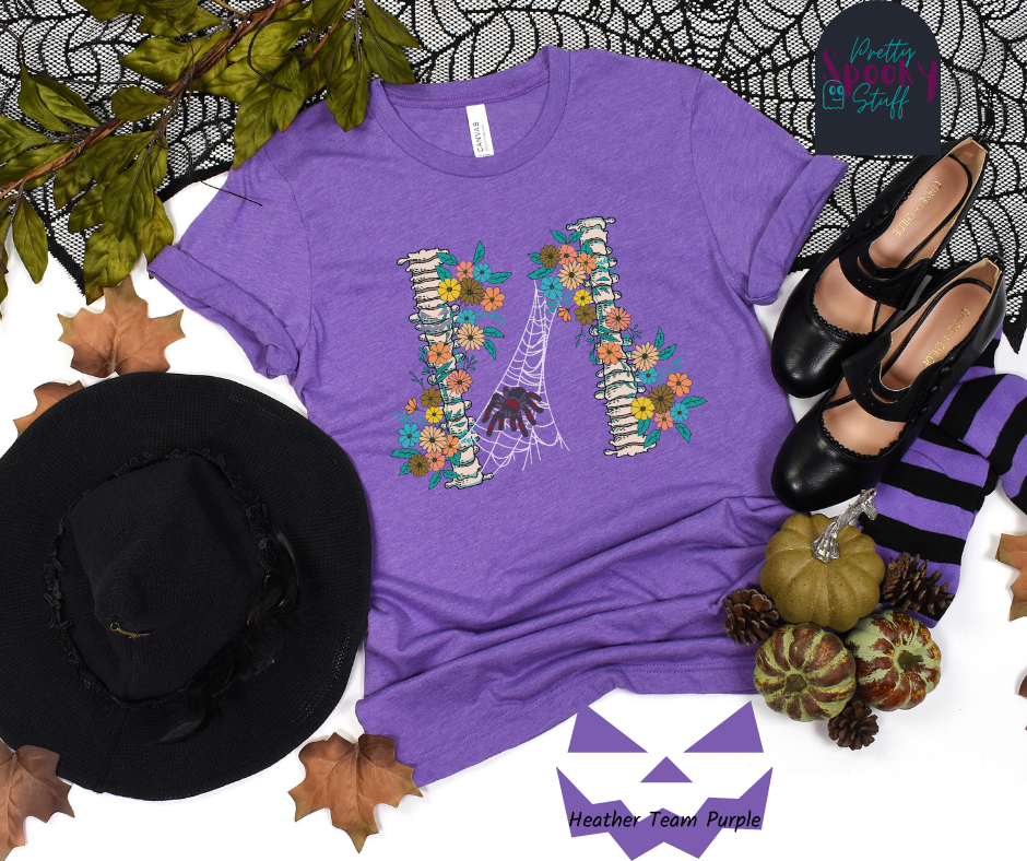 Spider Halloween shirt with two spine bones wrapped in vintage flowers, and a tarantula spider on a web between the two, in heather team purple.