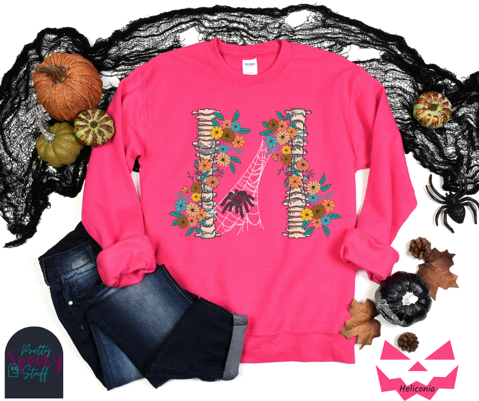 Spider Halloween sweatshirt with two spine bones wrapped in vintage flowers, and a tarantula spider on a web between the two, in heliconia.