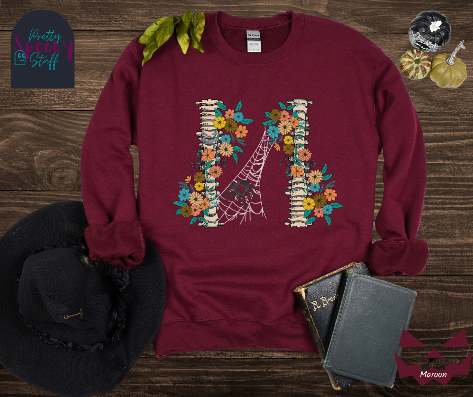 Spider Halloween sweatshirt with two spine bones wrapped in vintage flowers, and a tarantula spider on a web between the two, in maroon.
