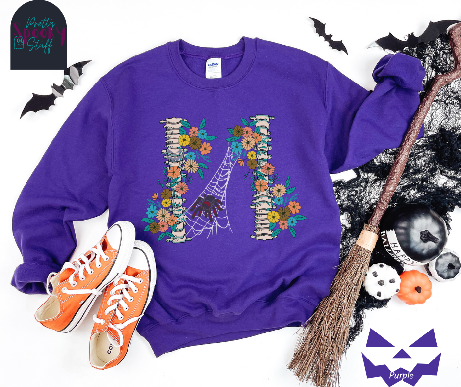 Spider Halloween sweatshirt with two spine bones wrapped in vintage flowers, and a tarantula spider on a web between the two, in purple.