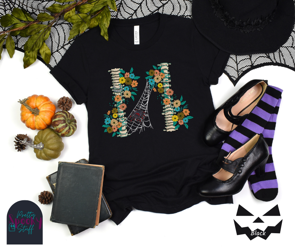 Spider Halloween shirt with two spine bones wrapped in vintage flowers, and a tarantula spider on a web between the two, in black.