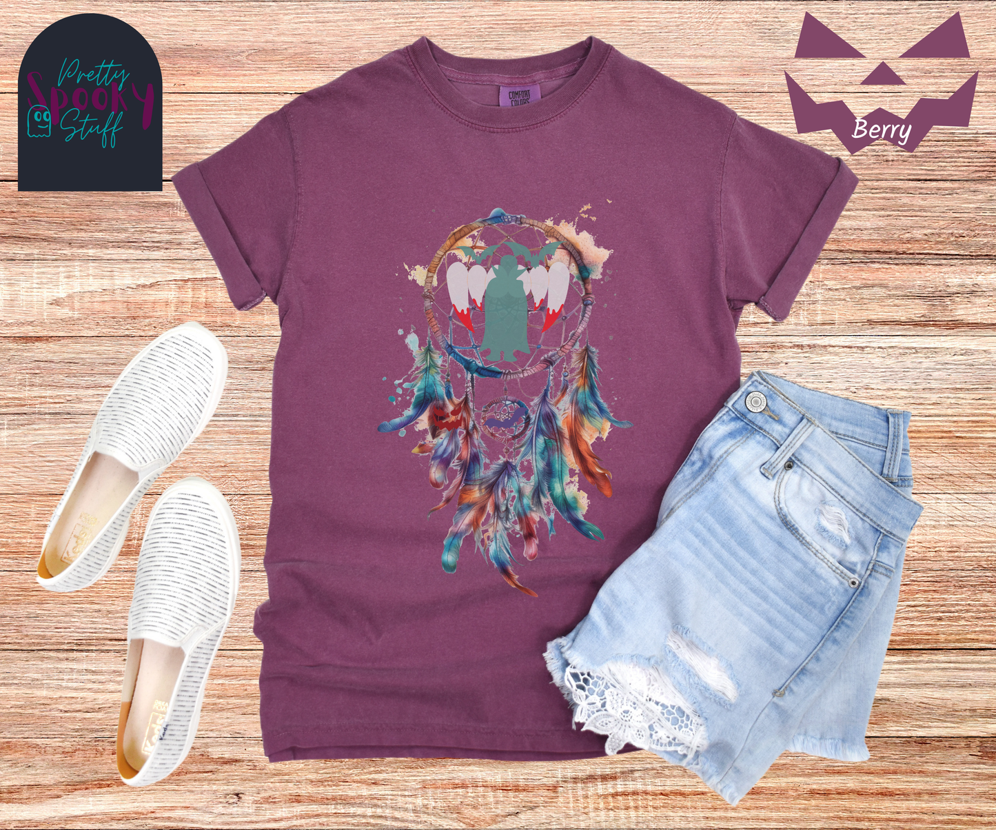 Halloween dream catcher shirt with watercolor aesthetic in blues and rusts, with teal vampire silhouette and bloody vampire teeth in main circle, bats and jack o' lantern face hidden amongst the several feathers hanging below, in berry.