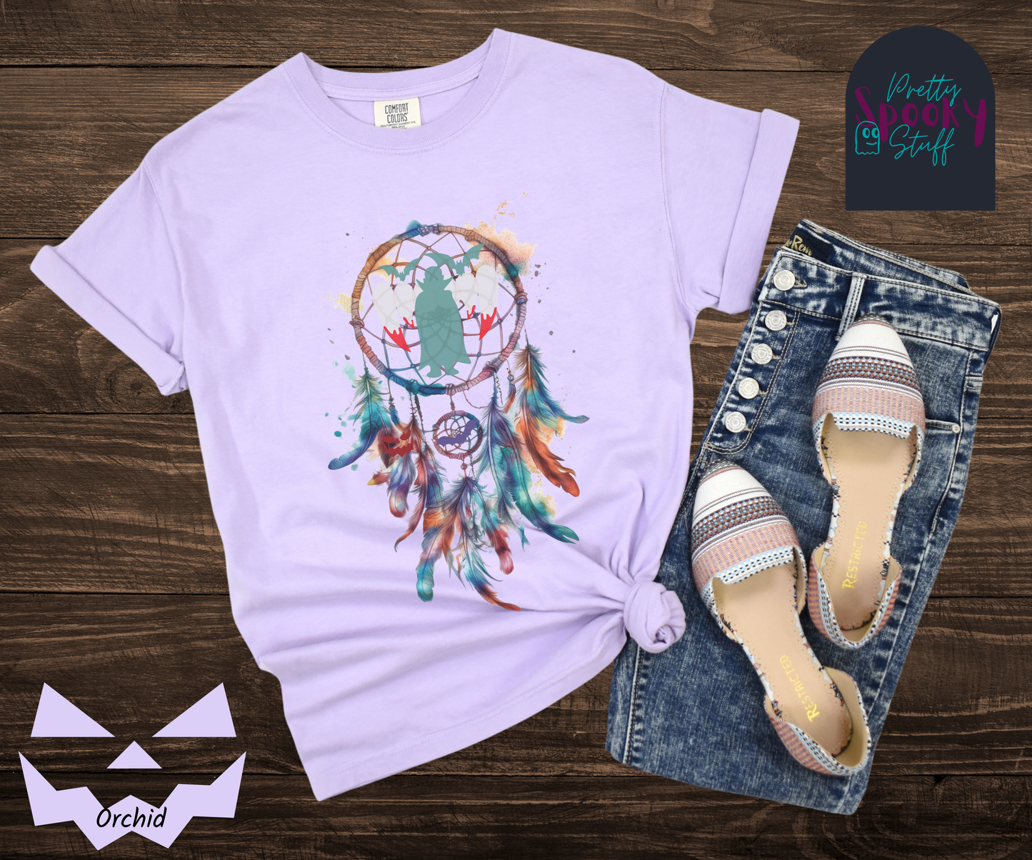 Halloween dream catcher shirt with watercolor aesthetic in blues and rusts, with teal vampire silhouette and bloody vampire teeth in main circle, bats and jack o' lantern face hidden amongst the several feathers hanging below, in orchid.