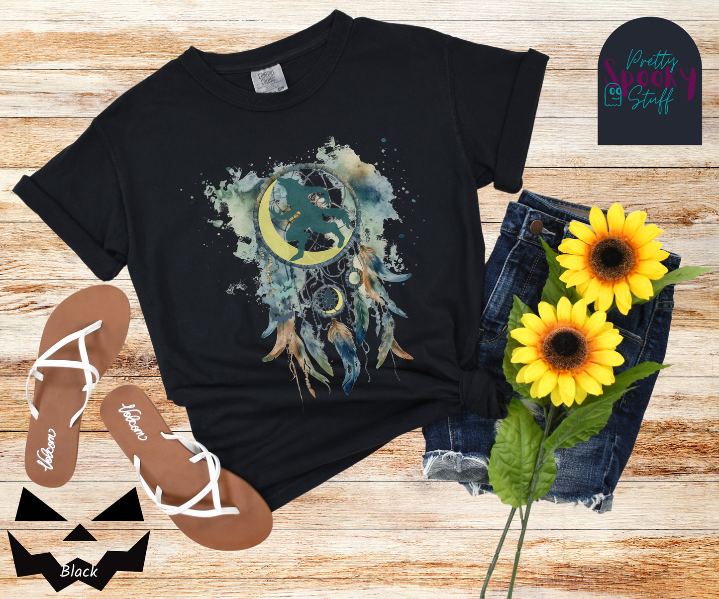 Halloween werewolf dreamcatcher shirt, watercolor aesthetic in blues and browns, featuring teal howling werewolf silhouette with yellow crescent moon in the main circle, with another werewolf/moon and jack o' lantern hiding amongst the several feathers and small circle hanging below, in black.