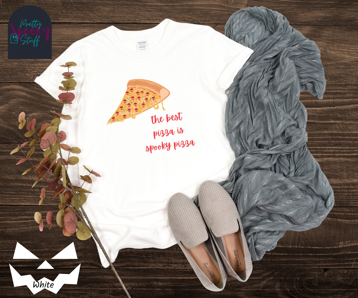 Pizza shirt with a slice of pepperoni pizza with skull shaped pepperonis and the words "the best pizza is spooky pizza" in red cursive font, in hite.