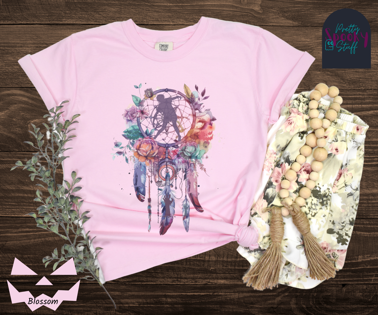 Zombie Halloween dreamcatcher shirt, watercolor aesthetic in purples, pinks, and teals, with purple zombie silhouette in the main circle, and zombie arm silhouettes hidden in the 3 feathers hanging below, in blossom.