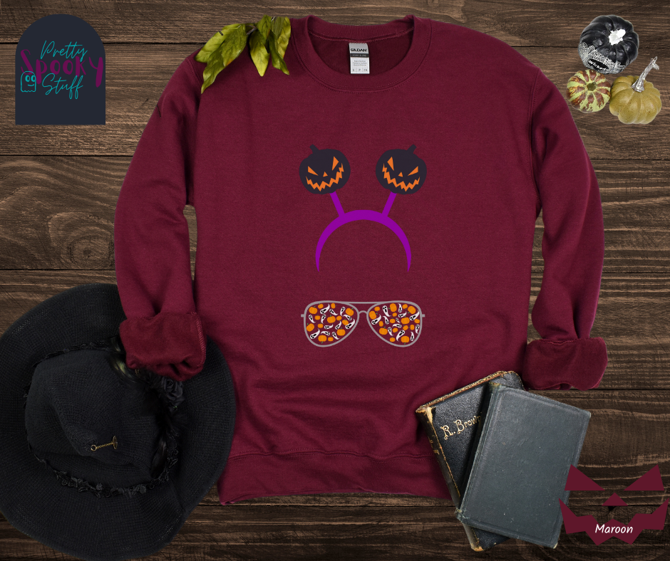 Halloween sweatshirt with aviator sunglasses filled with pumpkins and ghosts, and a purple headband with creepy jack o' lanterns, in maroon.