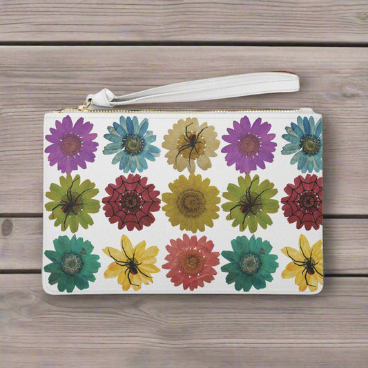 Spooky Girl Summer clutch bag with wrist strap and gold zipper,featuring 9 colorful daisies with three black widow spiders, and one web sitting on top of them, white background.