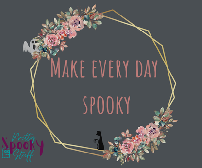 Typography shirt design closeup with the words "make every day spooky" in the middle of a gold circular frame with floral details and a black cat sitting on the bottom and a ghost peaking from the top.
