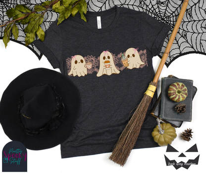Coquette Halloween shirt with three adorable ghosts, each enjoying their own coffee beverage, adorned with a pink bow, with light pink intricate lace design behind them, in dark grey heather