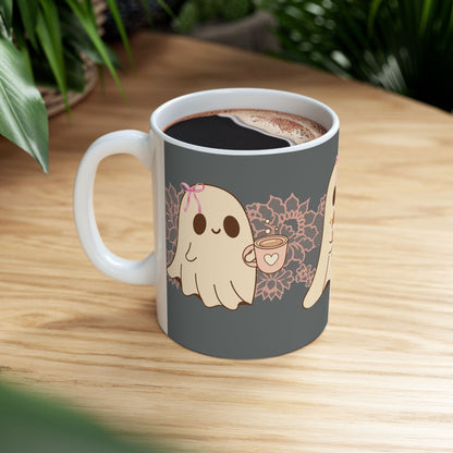 Ceramic Halloween coffee mug with three adorable ghosts, each enjoying their own coffee beverage, adorned with a pink bow, with light pink intricate lace design behind them, gray background, side view sitting on table.