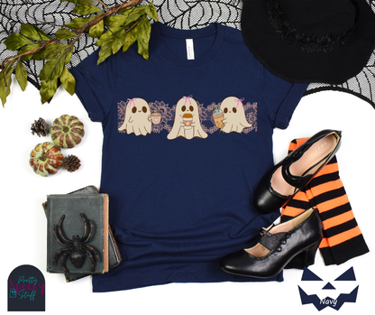 Coquette Halloween shirt with three adorable ghosts, each enjoying their own coffee beverage, adorned with a pink bow, with light pink intricate lace design behind them, in navy.