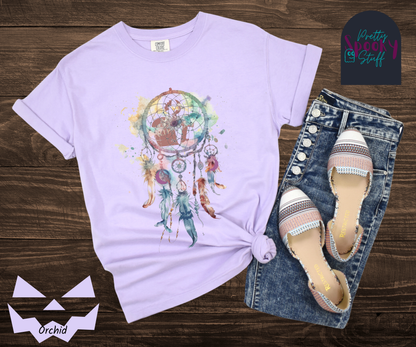 Gravestone dream catcher shirt, watercolor aesthetic dream catcher with blues, pinks and purples, 5 feathers hanging blow, mauve gravestones in main circle, and crescent moons hidden in feathers, in orchid.