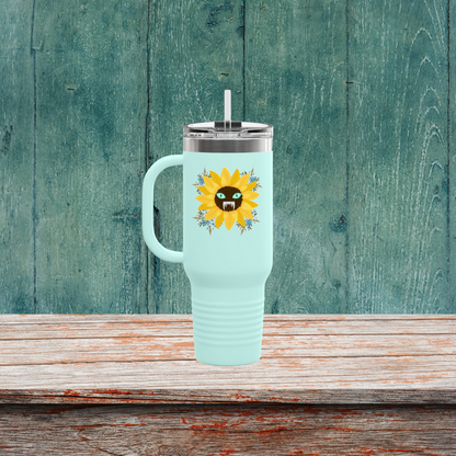 Spooky Girl Summer 40oz tumbler design featuring a sunflower with a menacing face in the middle(striking blue eyes and sharp teeth), with light blue florals in each corner, teal background. Sitting on a wooden table.
